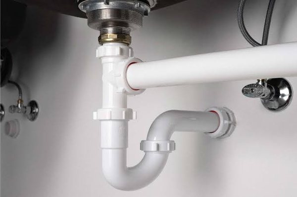 White PVC waste trap and pipework under a basin